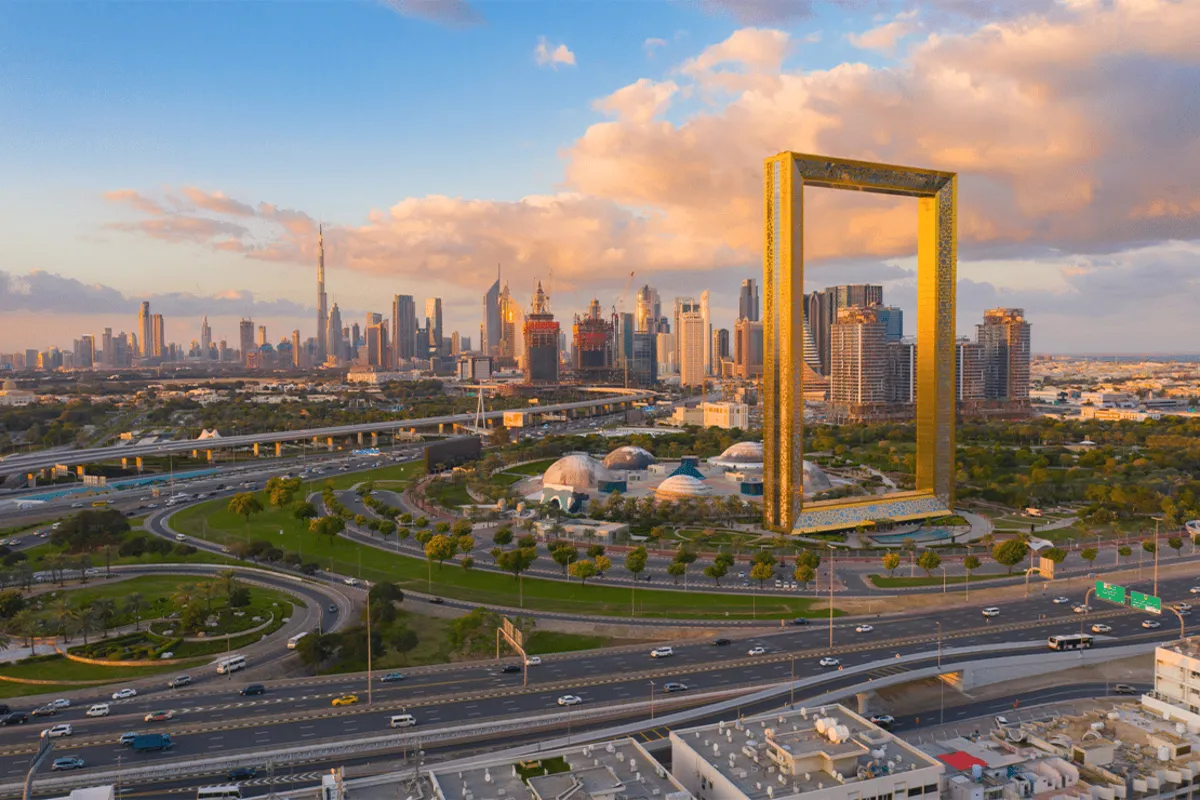 Establish company in dubai - Aerial view of a large golden frame structure with a bustling city skyline in the background.