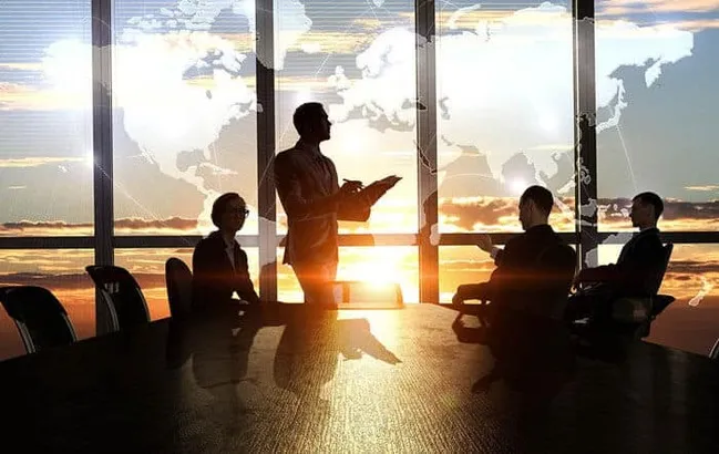  setting up a business in dubai - Silhouetted business meeting with world map background during sunset.