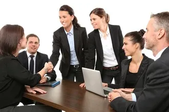 Business Setup Consultants in Dubai - Group of professionals in business attire around a table with a laptop. 