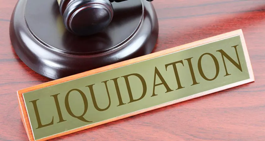 Establish company in dubai - A judge's gavel beside a 'LIQUIDATION' sign on a wooden surface.